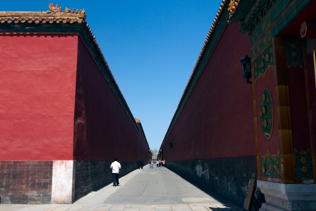 A quiet red-walled east path inside the Forbidden City under a blue sky