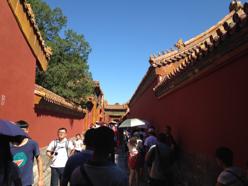 Visitors walking between red walls on the east side of the Forbidden City inner court