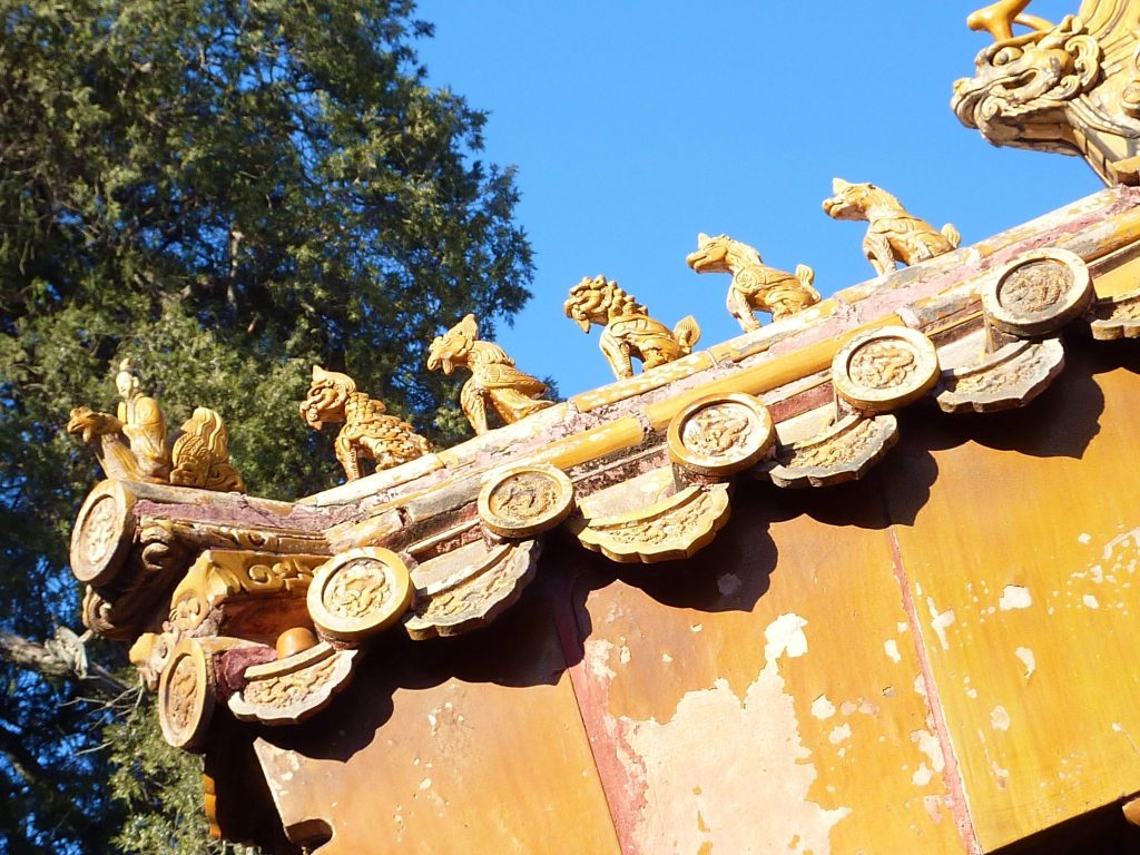 Small glazed roof animals along a yellow tiled roof in the Forbidden City